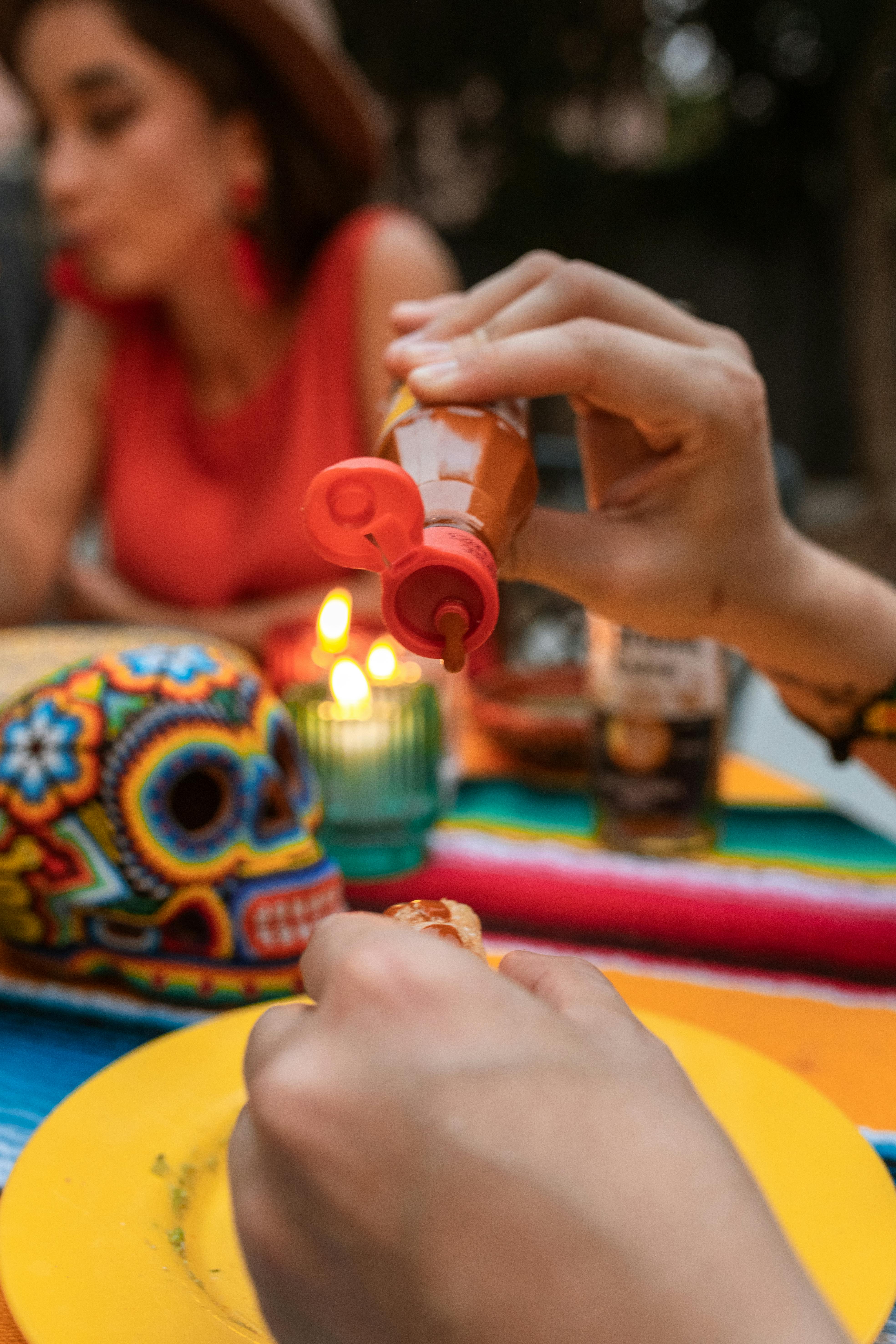 A person pouring hot sauce onto a dish, showcasing different ways to enjoy spicy flavors